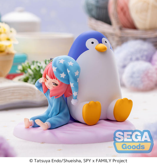 An Anya Forger figure produced by Luminasta. It features a sleepy looking Anya in blue pajamas, sitting next to an over sized penguin. 